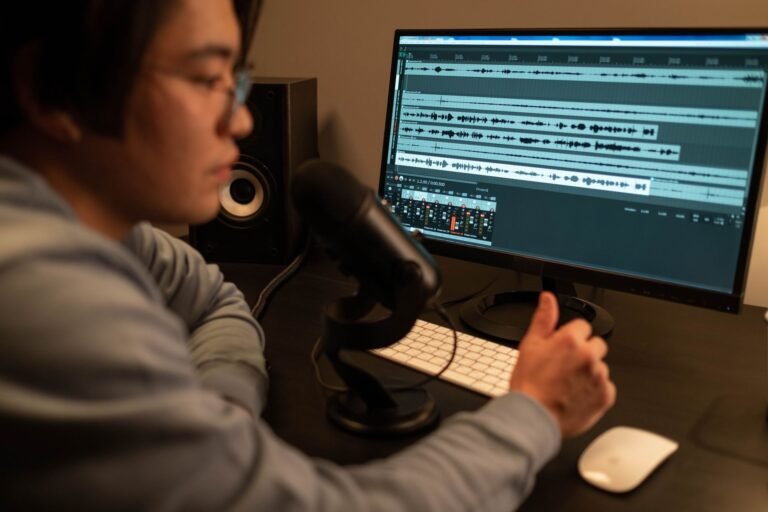 Audio editor with headphones editing audiobook narration on a computer