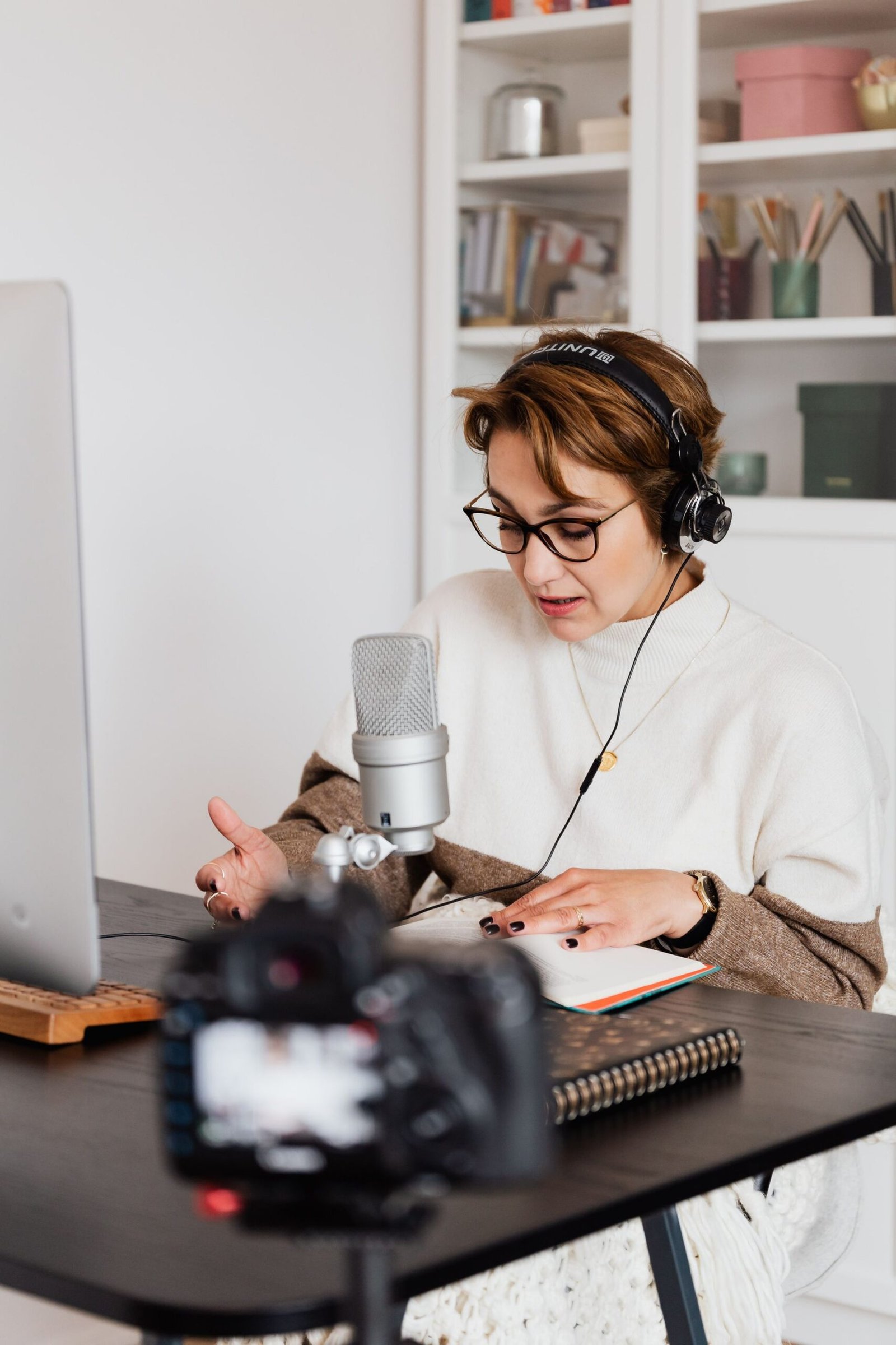 Audiobook narrator with headphones reading a book into a studio microphone